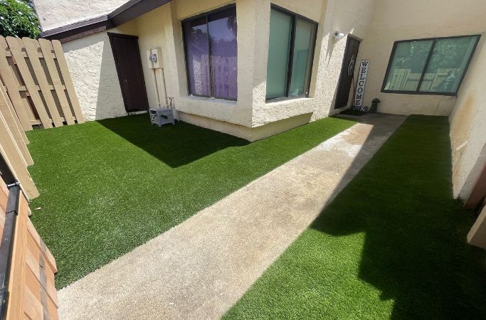 On-Time Turf team member demonstrating the advantages of artificial grass installation in Miami Beach, FL, for a low-maintenance, green lawn.