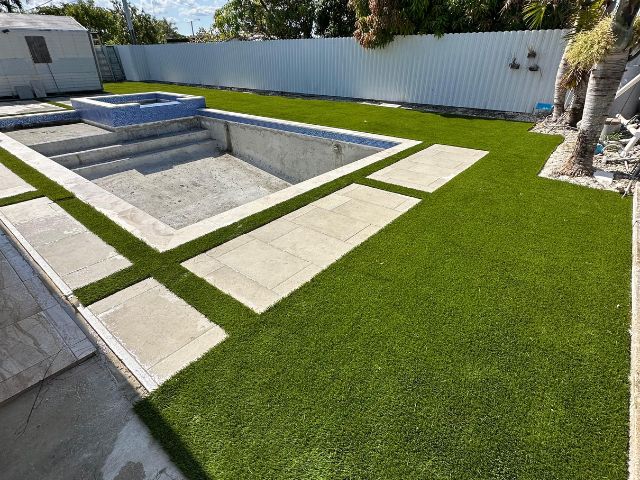 A skilled On-Time Turf employee installing artificial grass in Fort Lauderdale, FL, creating a lush, maintenance-free lawn for a residential property.